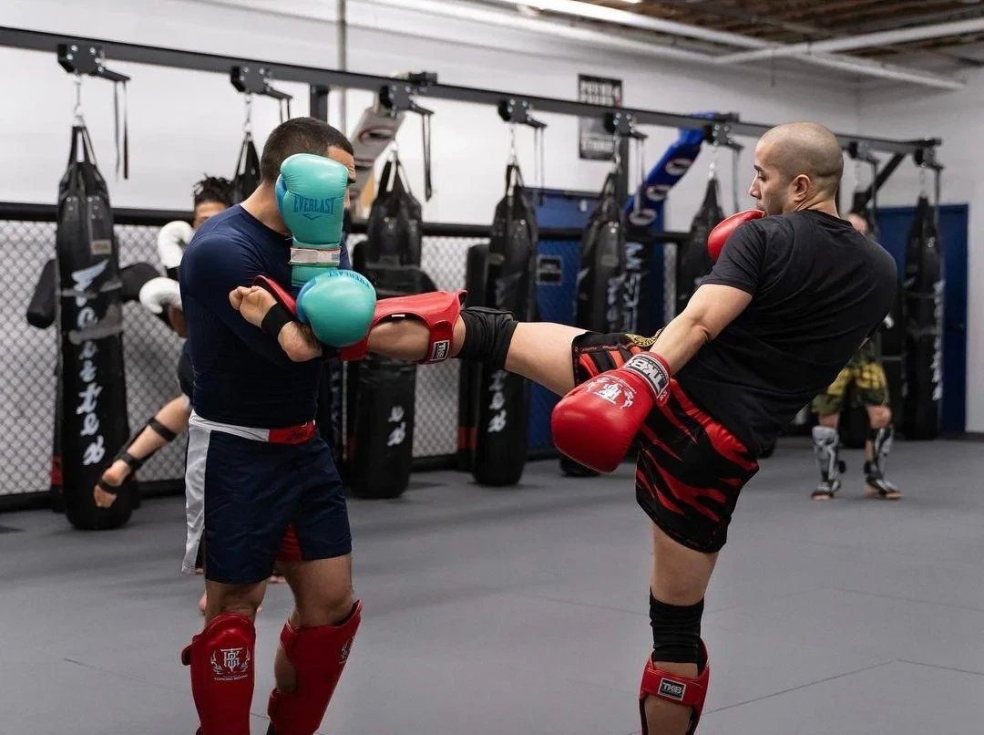 Two Pound 4 Pound students practicing a Muay Thai body kick during partner drilling class in Littleton