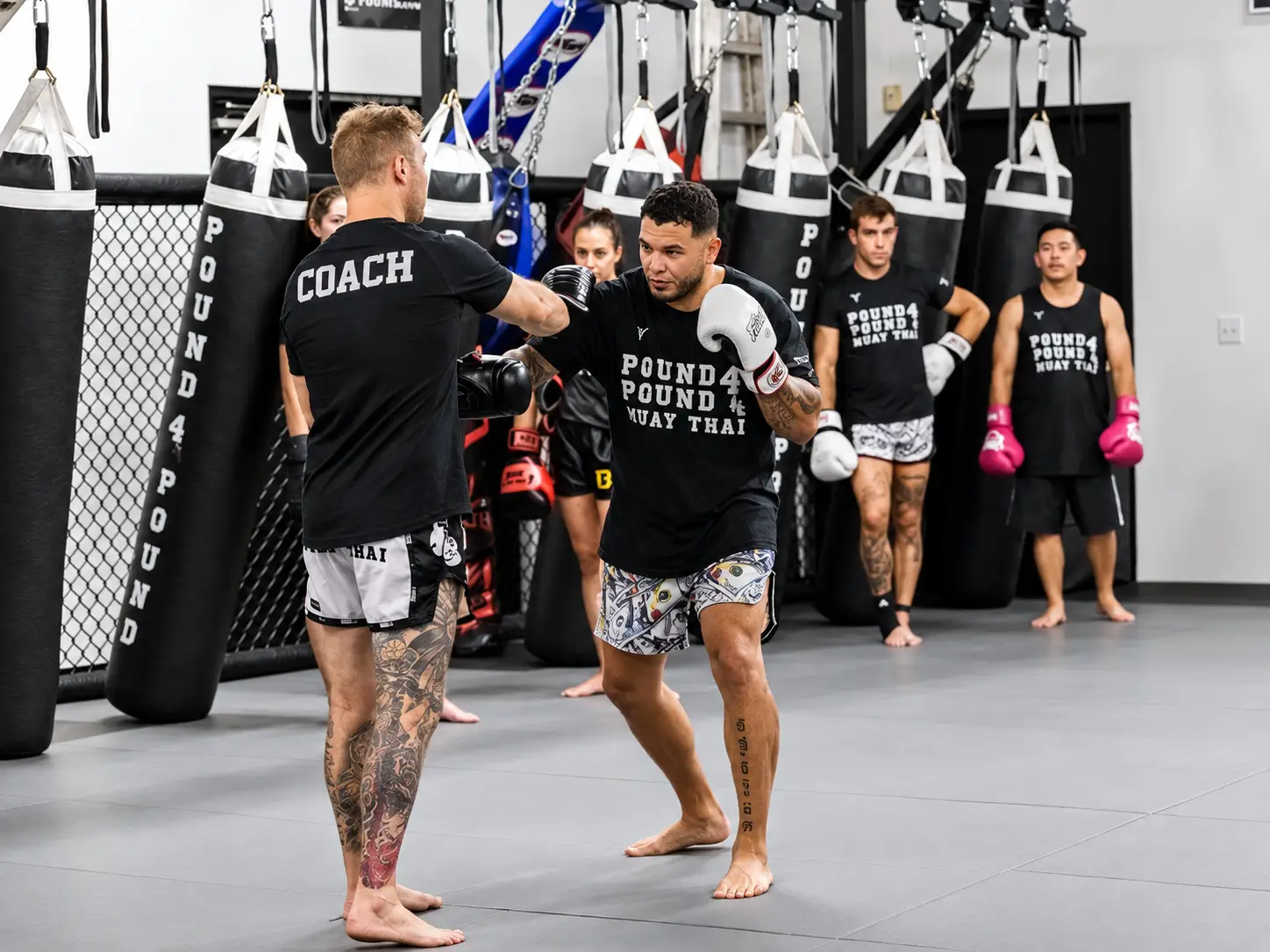 Muay Thai coach working on pad drills with a student during class at Pound 4 Pound in Littleton, Colorado