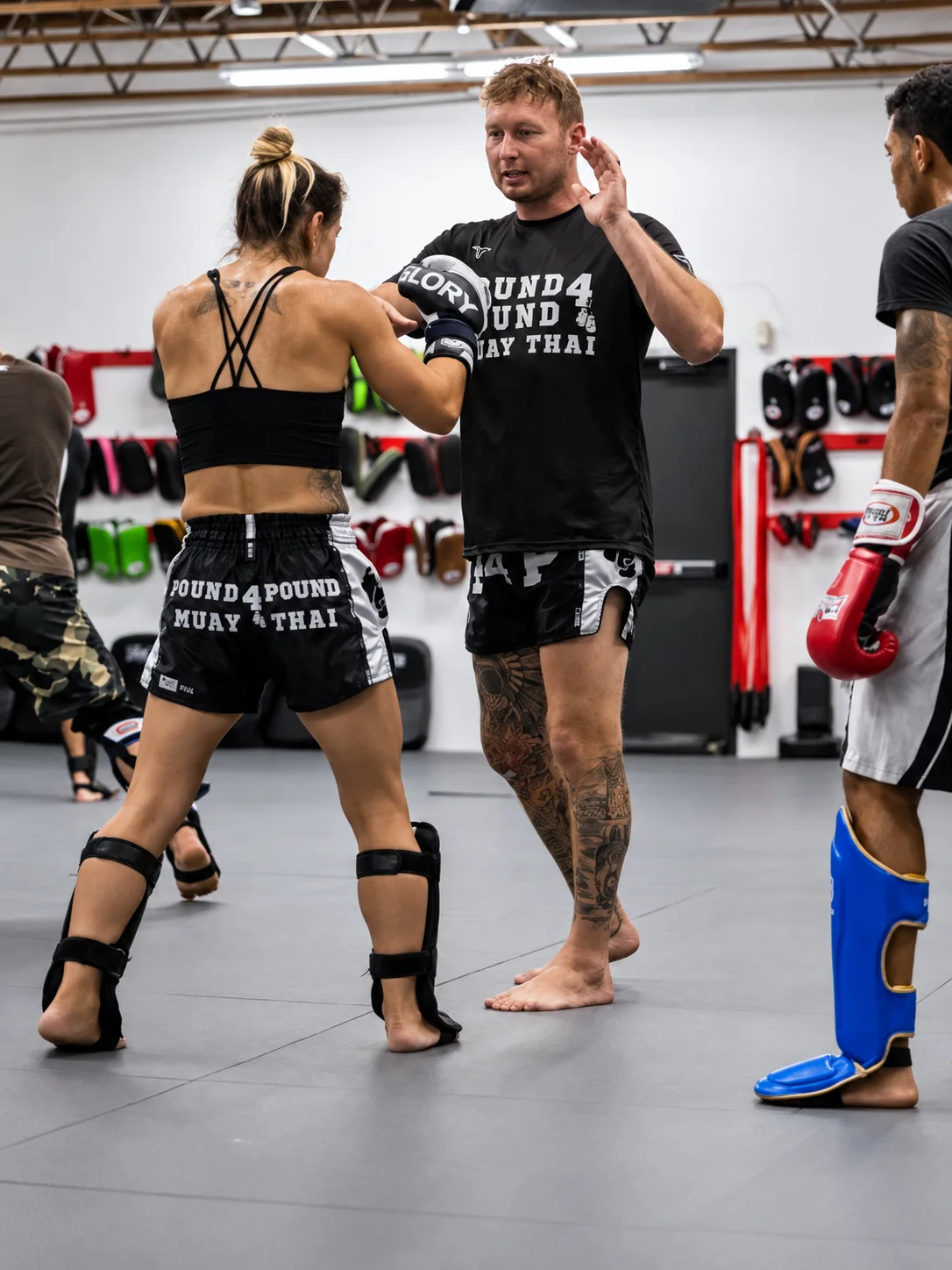 Coach teaching Muay Thai technique to a woman during group training at Pound 4 Pound in Littleton